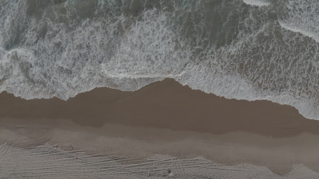 top view of waves gently breaking on beach sand