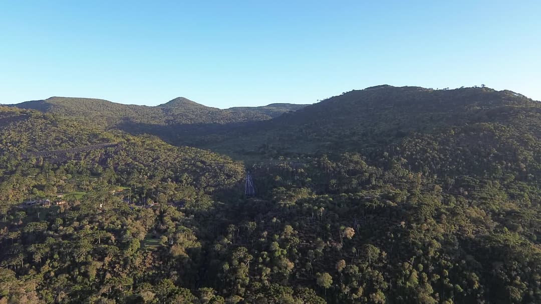 Sobrevoo saindo de um chalé com vista para o morro da igreja e a cascata veu de noiva