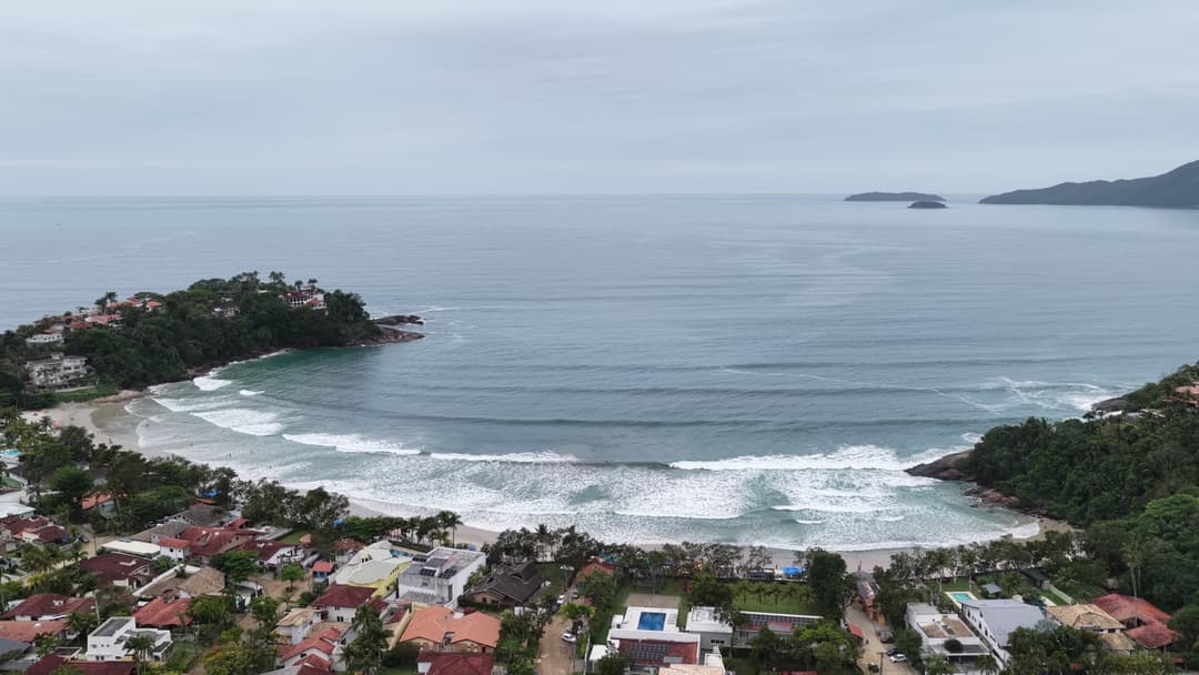 Praia em formato de enseada com casas à beira-mar