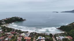 Praia em formato de enseada com casas à beira-mar