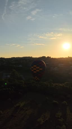 Balão colorido sobrevoando ao pôr do sol