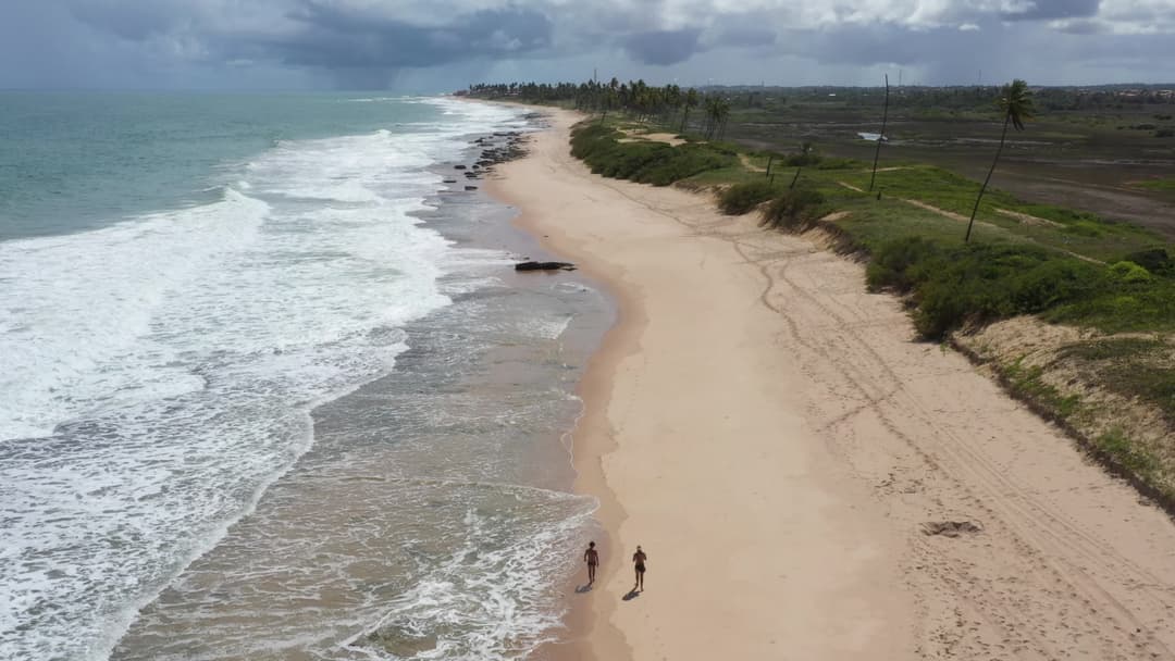 Praia deserta com mar agitado e céu nublado