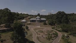 Estufa central rodeada por jardins e trilhas