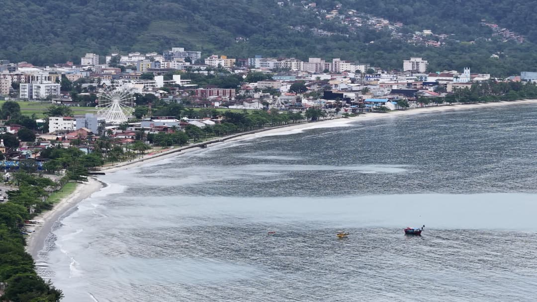 Praia urbana com roda gigante à beira-mar