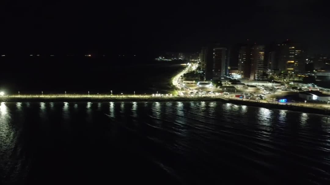 Orla da Península iluminada à noite com reflexos no mar