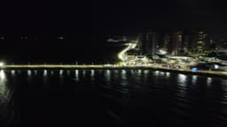 Orla da Península iluminada à noite com reflexos no mar