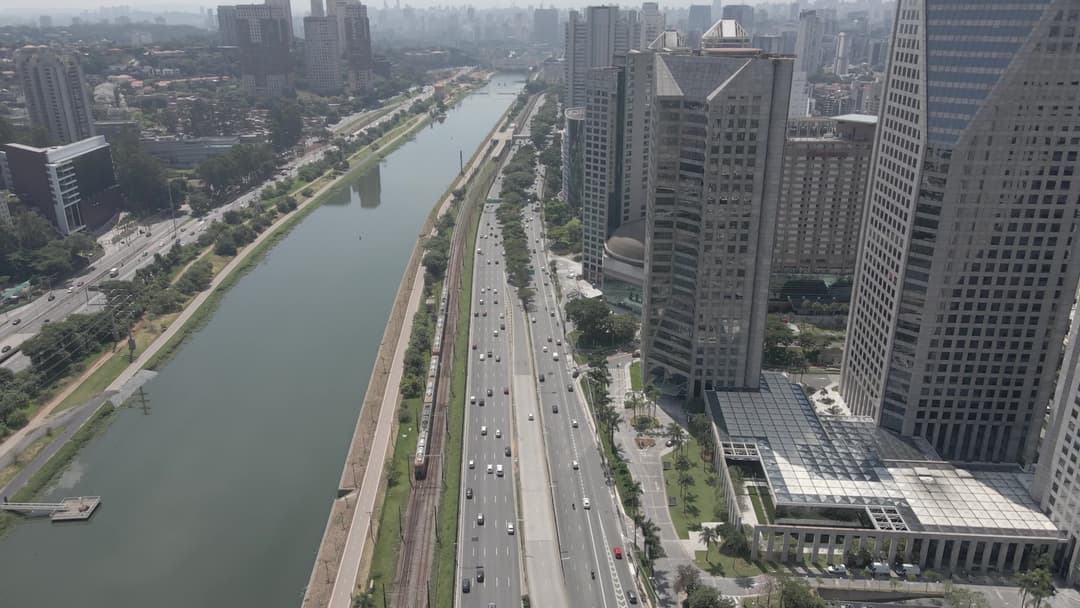 Avenida movimentada entre prédios e rio