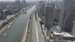 Avenida movimentada entre prédios e rio
