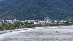 Roda-gigante à beira-mar com montanha ao fundo