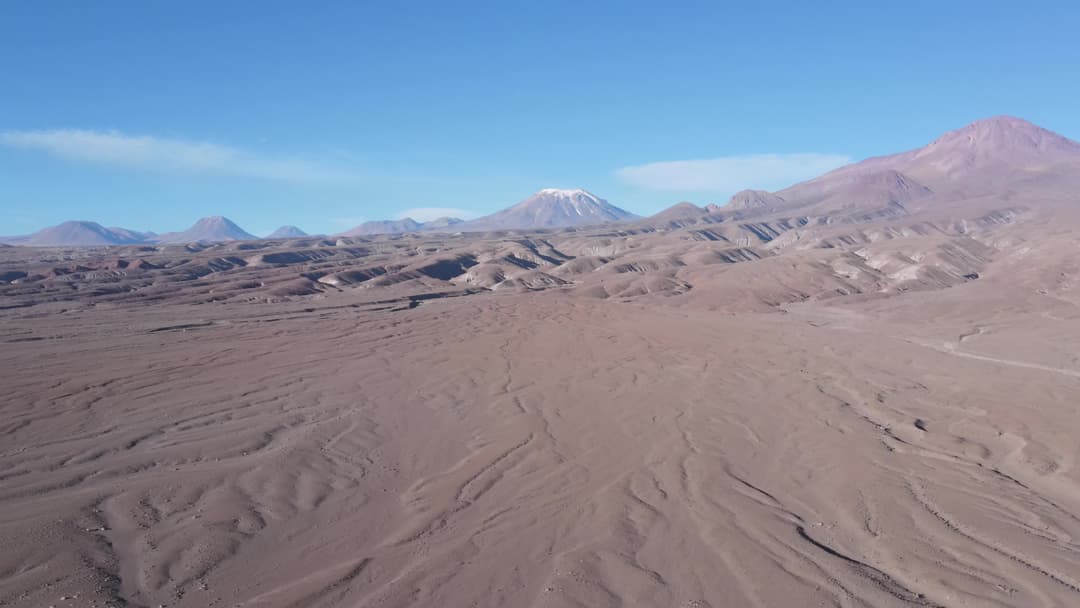 Deserto de areia com vulcão ao fundo
