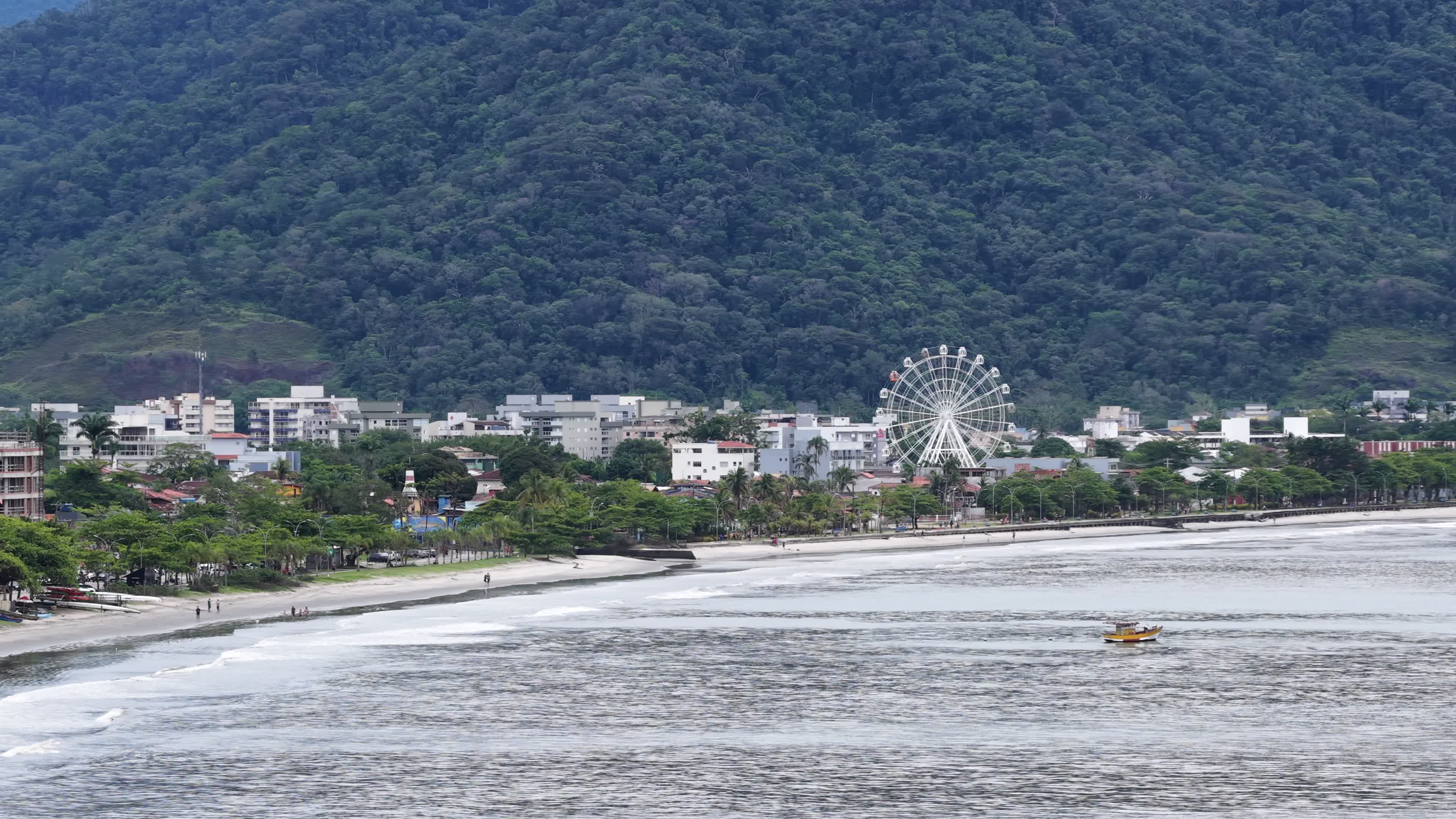 Roda-gigante à beira-mar com montanha ao fundo