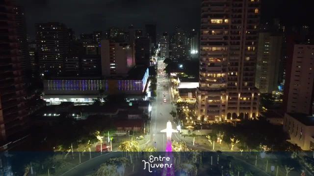 Avenida iluminada com monumento central à noite