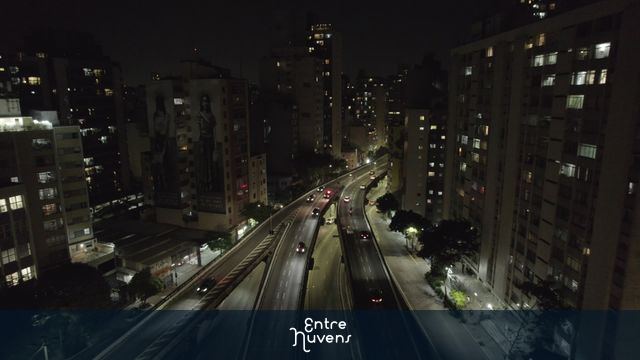 Avenida movimentada entre prédios à noite