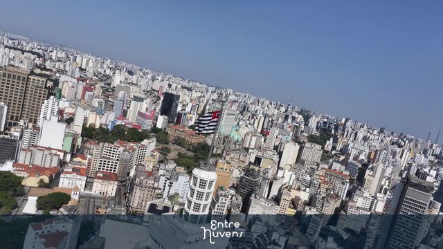 Bandeira de São Paulo no topo da cidade com metrópole à volta