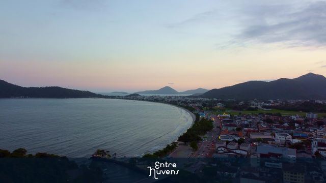Entardecer na praia e cidade com montanhas ao fundo