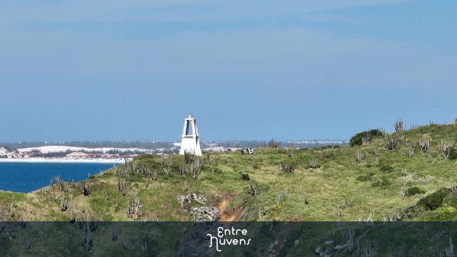 Farol branco em destaque na paisagem verde em Cabo Frio RJ