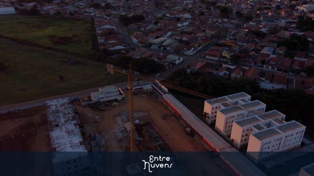 Grua (guindaste) operando na construção de condomínio residencial ao pôr do sol - 4k  — vídeo aéreo de Taubaté
