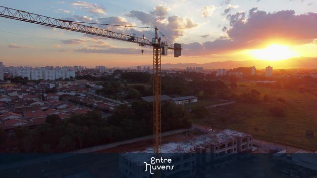 Grua (guindaste) operando na construção de condomínio residencial ao pôr do sol - 4k — vídeo aéreo de Taubaté