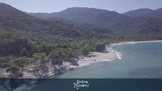 Litoral em praia afastada, montanhas e vegetação