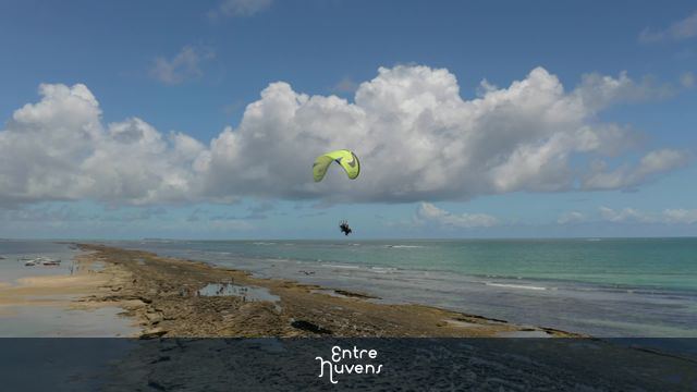 motorized paraglider flying low over the beach sand in Porto de Galinhas