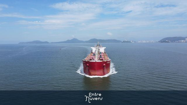 Navio cargueiro vermelho corta o mar azul