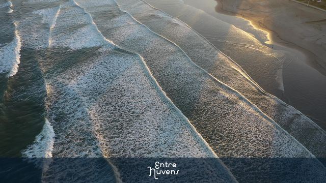 Ondas paralelas quebrando no pôr do sol em Santos