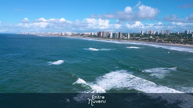 Orla urbana com mar azul e prédios ao fundo