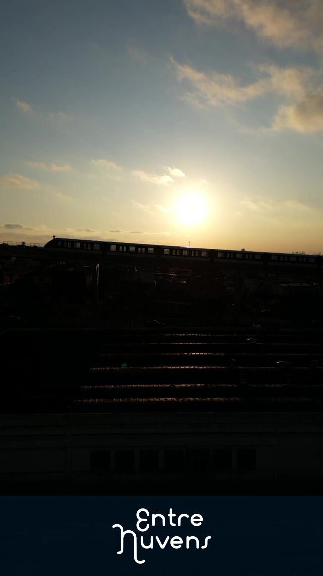 Por do sol com monotrilho de silhueta passando pela filmagem.
