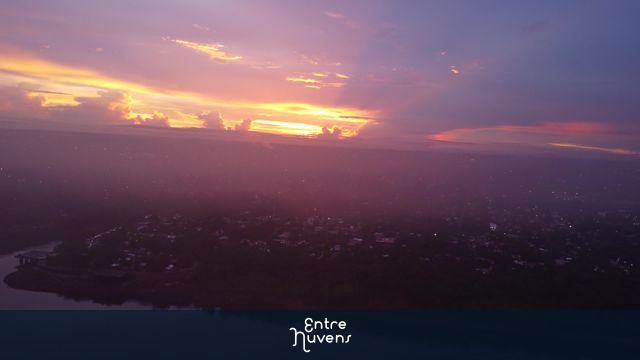 Pôr do sol radiantecom névoa sobre cidade, rio e poluição