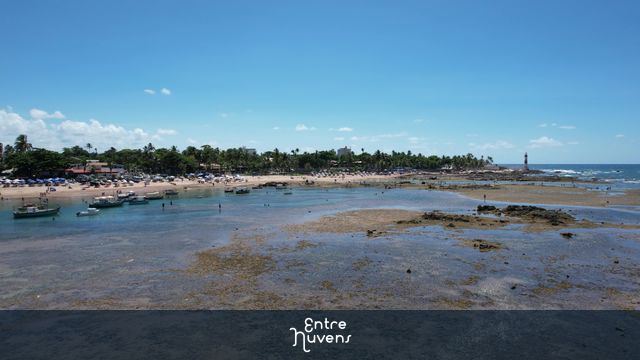 Praia com piscinas naturais e farol ao fundo