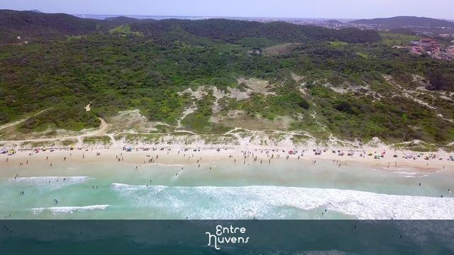 Praia do Peró com mar verde, banhistas e vegetação preservada — vídeo aéreo de Cabo Frio