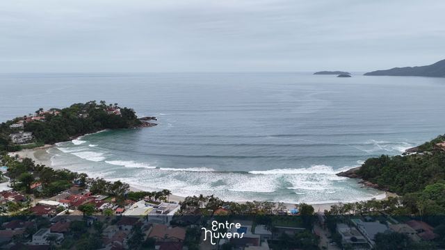 Praia em formato de enseada com casas à beira-mar
