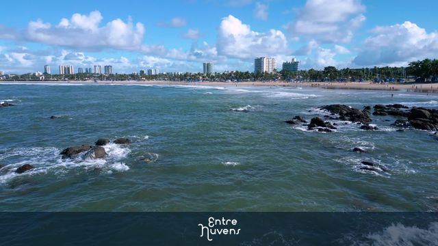 Praia urbana com águas e rochas em destaque