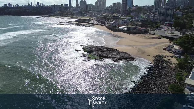 Praia urbana com rochas e skyline ao fundo
