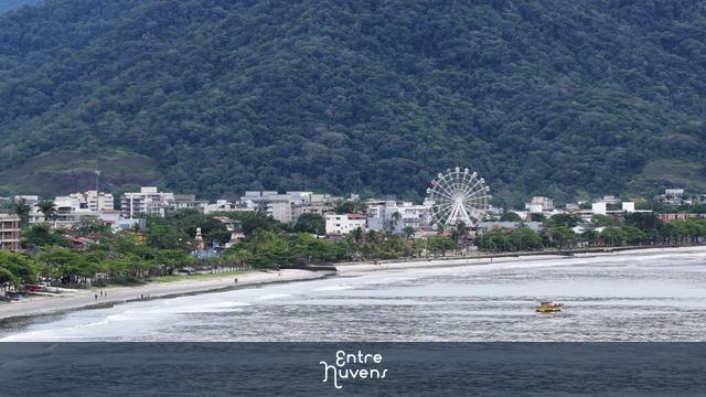 Roda-gigante à beira-mar com montanha ao fundo