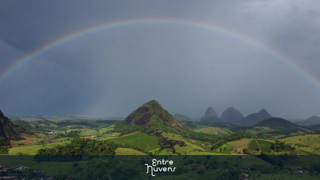 Um fim de tarde com um belíssimo por do sol com arco-íris na cidade sob as montanhas.  — vídeo aéreo de Vila Pavão