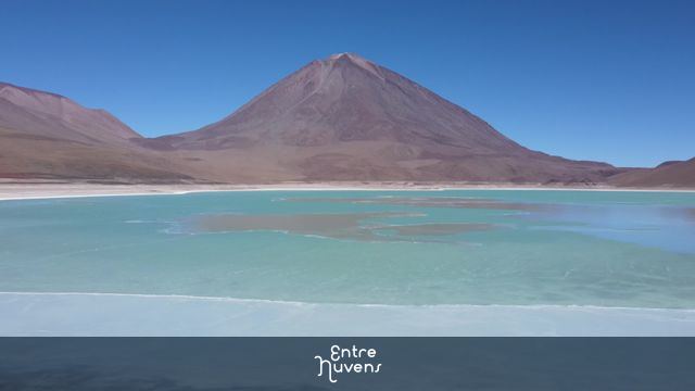 Vulcão imponente e lago turquesa no deserto